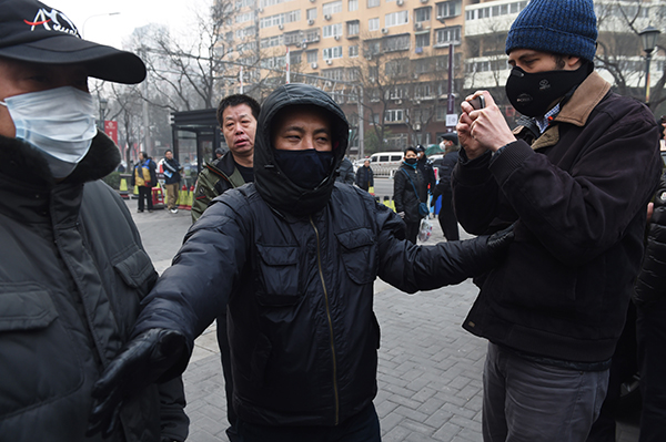 Plainclothes security officers tussle with a journalist outside the trial of a prominent human rights lawyer in Beijing on December 22, 2015. Journalists who document human rights abuses or protests are at risk of jail in China. (AFP/Greg Baker)