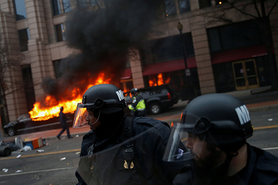 Police stand guard as a limousine set on fire by activists in Washington burns in the background, January 20, 2017. (Reuters/Adrees Latif)