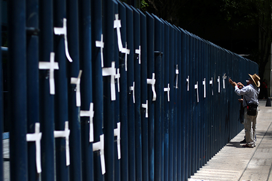 A man attaches crosses to the fence of the attorney general's office (PGR) in Mexico City to protest the murder of journalists, April 1, 2017. (Reuters/Edgard Garrido)