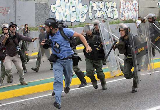 A Reuters photojournalist runs as Venezuelan National Guard soldiers charge during a protest outside the Supreme Court in Caracas on March 31. Several journalists have been injured covering the unrest. (AP/Ariana Cubillos)