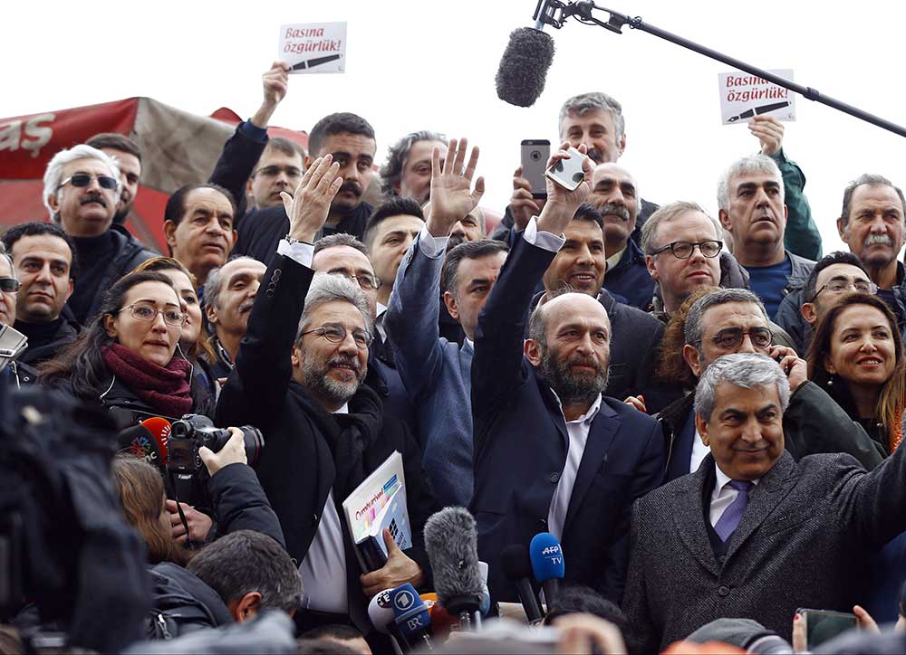 Can Dündar, then editor-in-chief of Cumhuriyet, center left, and Ankara bureau chief Erdem Gül greet supporters as they arrive for a court hearing in Istanbul in March 2016. (Reuters/Osman Orsal)