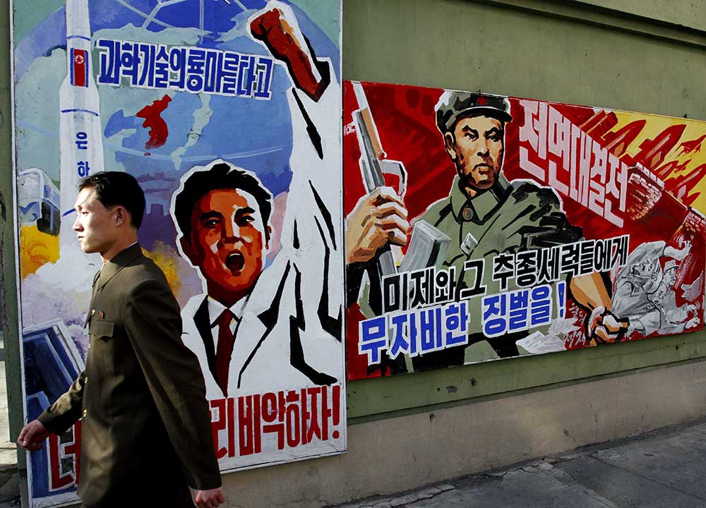 A North Korean man walks past propaganda posters in Pyongyang, North Korea, that threaten punishment to the 'U.S. imperialists and their allies.' (AP/Kim Kwang Hyon)