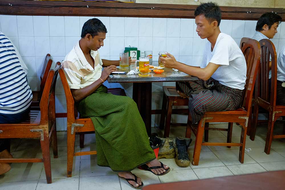 Young men check their Facebook pages at a restaurant in Yangon, Myanmar, over beers and dinner. The social network is improving access to news in remote areas. (Jerry Redfern)