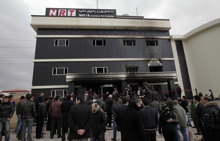 Staff and neighbors of the NRT satellite channel gather outside the station's damaged office in Sulaymaniyah, February 20, 2011. Gunmen raided and set fire to the television station in northern Iraq. (Reuters)