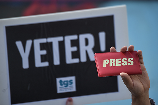 A journalist holds a press sign next to a placard reading 'Enough!' during a World Press Freedom Day rally in Istanbul. Turkey is a leading jailer of journalists. (AFP/Ozan Kose)