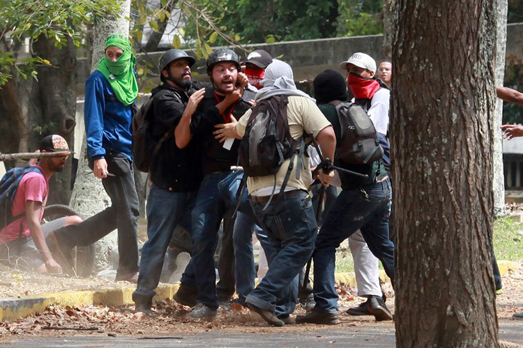 Miembros de un 'colectivo', un grupo armado progubernamental, agreden a Leonardo Rodríguez (centro), un reportero gráfico con el diario El Nacional, mientras cubría a una manifestación de estudiantes en la Universidad Central de Venezuela (UCV) en Caracas, el 3 de abril de 2014. (AFP/Federico Parra)