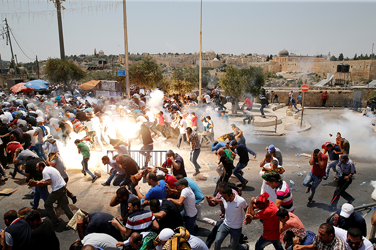 Palestinians run from tear gas and sound grenades at a July 21, 2017, protest outside Jerusalem's old city. (Reuters/Ammar Awad)