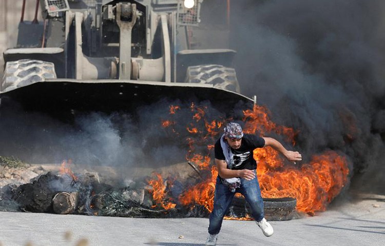 A Palestinian protester runs from Israeli military machinery in the West Bank village of Khobar, near Ramallah, July 22, 2017. (Reuters/Mohamad Torokman)