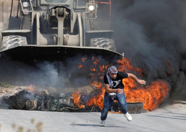 A Palestinian protester runs from Israeli military machinery in the West Bank village of Khobar, near Ramallah, July 22, 2017. (Reuters/Mohamad Torokman)