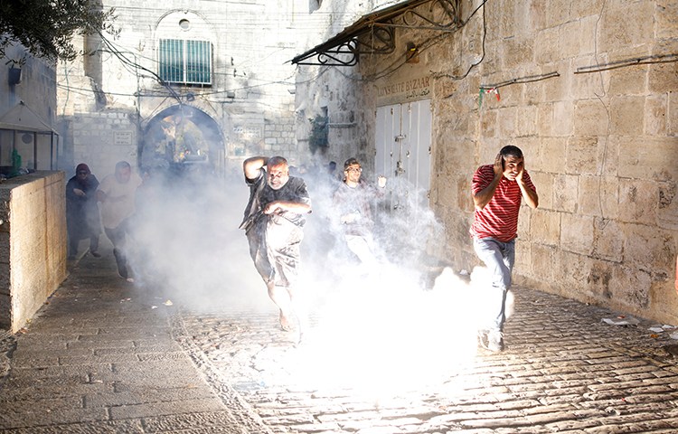 Palestinians run from tear gas and stun grenades in the old city of Jerusalem, July 27, 2017. (Reuters/Amir Cohen)