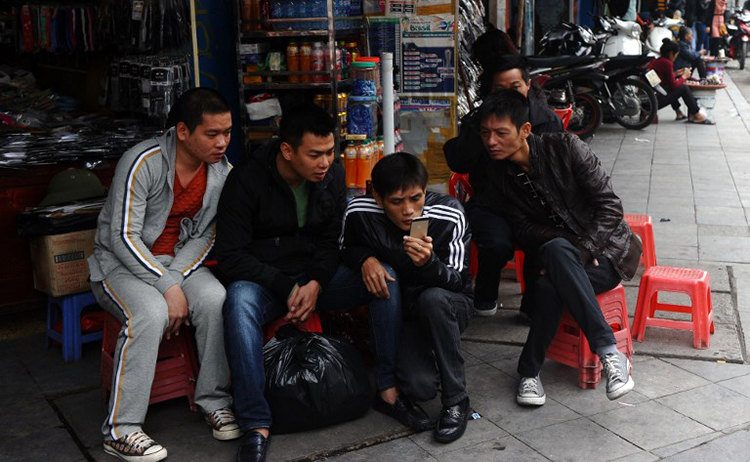 In this December 5, 2014, file photo, men read the news on a mobile phone in central Hanoi. (AFP/Hoang Dinh Nam)