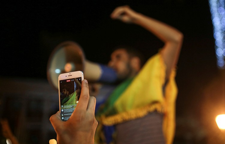 A man broadcasts via Facebook during a demonstration in Rabat in support of protests in the northern Rif region. Police arrested a journalist who was on his way to cover the protests in Rif. (AP Photo/Mosa'ab Elshamy)