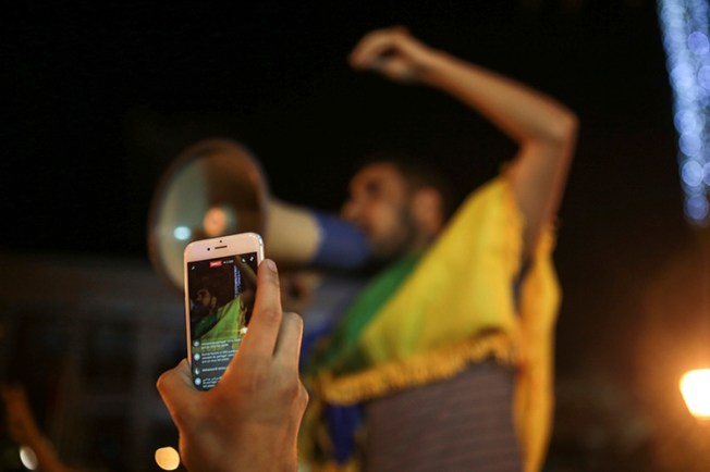 A man broadcasts via Facebook during a demonstration in Rabat in support of protests in the northern Rif region. Police arrested a journalist who was on his way to cover the protests in Rif. (AP Photo/Mosa'ab Elshamy)