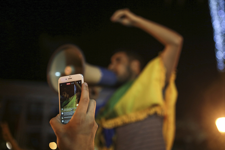 A man broadcasts via Facebook during a demonstration in Rabat in support of protests in the northern Rif region. Police arrested a journalist who was on his way to cover the protests in Rif. (AP Photo/Mosa'ab Elshamy)