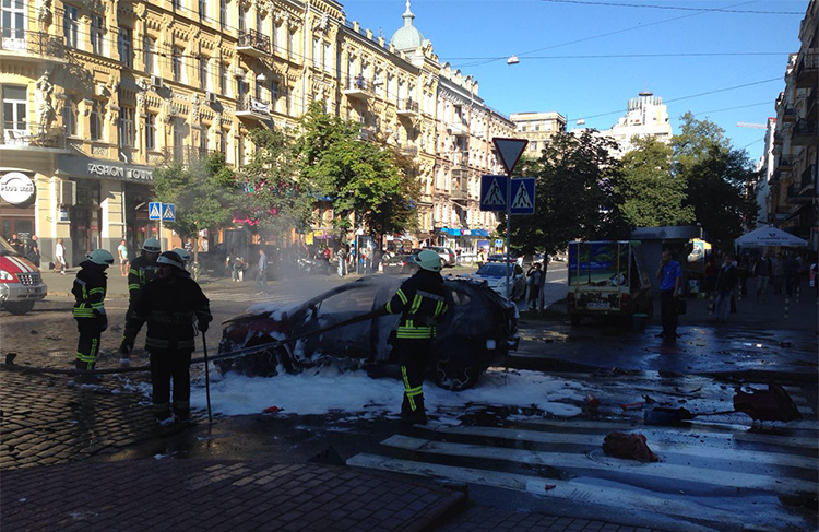 In this photograph taken by Olena Prytula before she realized her partner was in the explosion, firefighters douse the vehicle in a Kiev street. (Olena Prytula)