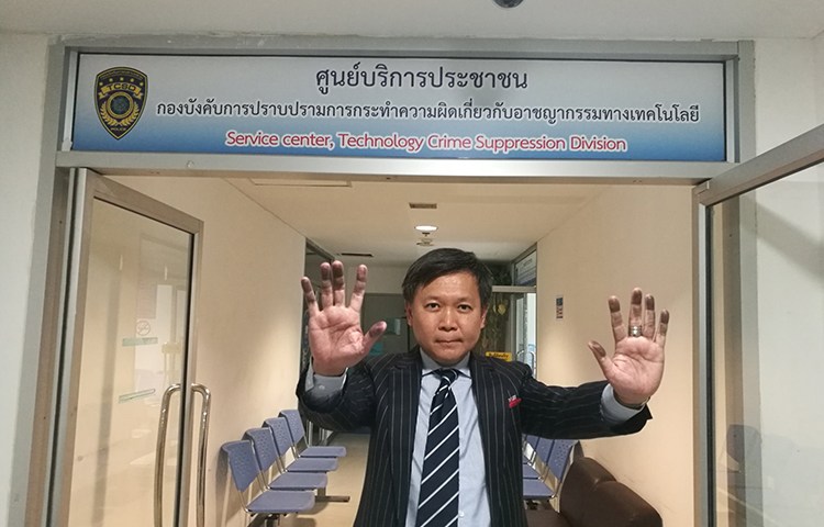 Thai columnist Pravit Rojanaphruk raises his hands, stained by ink from being fingerprinted, at the Royal Thai Police's Technology Crime Suppression Division in Bangkok, August 8, 2017. (Pravit Rojanaphruk)