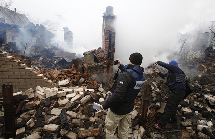 Members of an OSCE monitoring mission take photos of house in Avdiivka after shelling by pro-Russian rebels in February 2017. Ukraine has barred two Spanish freelancers from entry to the country over their reporting on the conflict in the east. (AFP/Anatolii Stepanov)