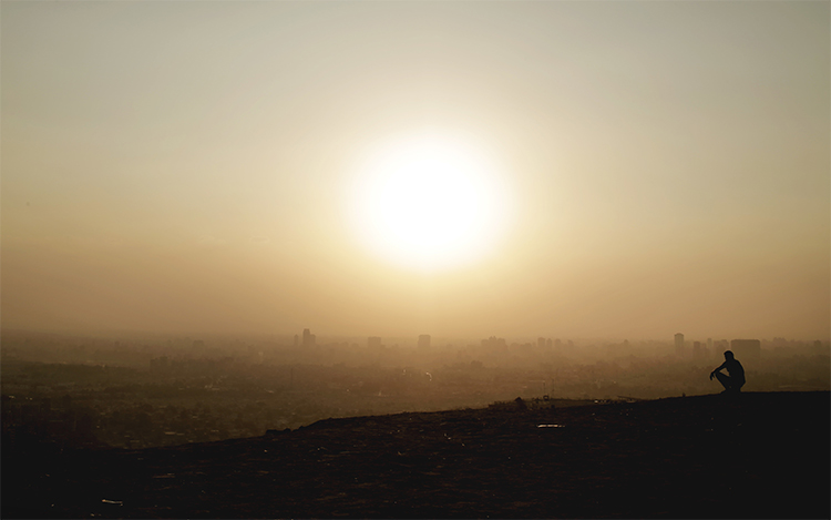 A man sits on a cliff overlooking Greater Cairo in August. An Egyptian news website says it believes one of its journalists is detained by police in the region. (AP/Nariman El-Mofty)