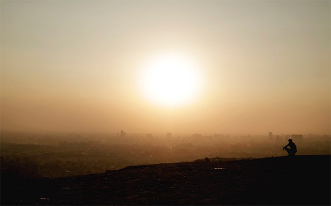 A man sits on a cliff overlooking Greater Cairo in August. An Egyptian news website says it believes one of its journalists is detained by police in the region. (AP/Nariman El-Mofty)