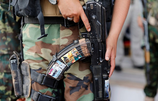 A soldier holds a rifle with photos of Yemen's former president Ali Abdullah Saleh, right, and his son, Ahmed, during a rally in Sanaa, Yemen on August 24, 2017. (Reuters/Khaled Abdullah)