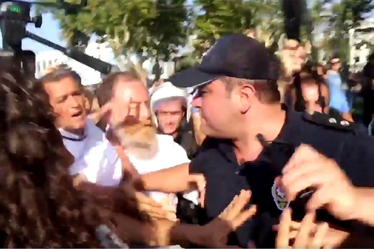 A screen shot of a Dihaber video shows a police officer scuffling with journalists at an August 6 opposition party protest in Istanbul.