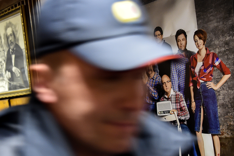 A police officer walks past a photograph of Ekho Moskvy journalists, including Tatyana Felgengauer, seen on the right, at the station's Moscow office. An assailant stabbed Felgengauer on October 23, 2017. (AFP/Vasily Maximov)