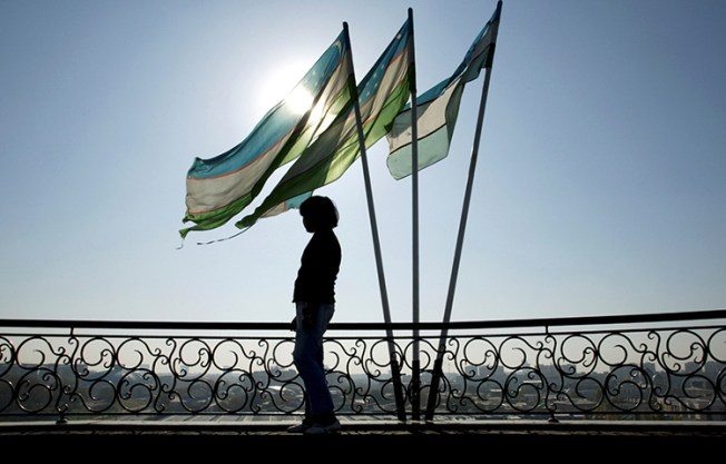 A girl is silhouetted against the sun standing next to Uzbek flags in Tashkent. Uzbek journalist Bobomurod Abdullaev went missing on September 27, 2017, and has since been secretly tried in a criminal court in Tashkent. (Reuters/Shamil Zhumatov)