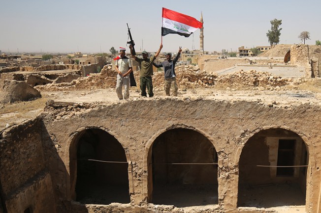 Members of the Popular Mobilisation Units pose with the Iraqi flag in Tal Afar. Authorities in Iraq and Syria who relied on militias to help fight Islamic State must now decide what to do with the groups. (AFP/Ahmad al-Rubaye)