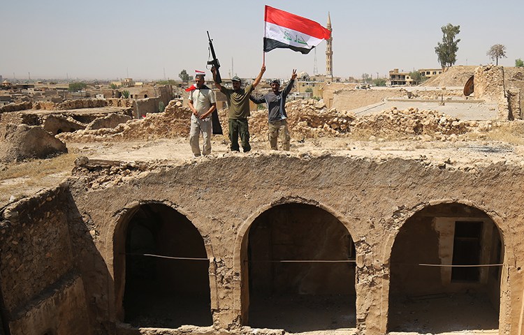 Members of the Popular Mobilisation Units pose with the Iraqi flag in Tal Afar. Authorities in Iraq and Syria who relied on militias to help fight Islamic State must now decide what to do with the groups. (AFP/Ahmad al-Rubaye)