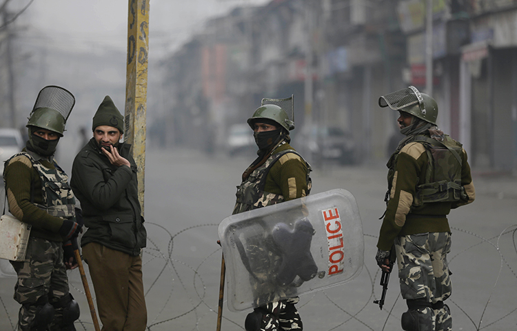 Indian paramilitary soldiers and a policeman, second from left, guard a checkpoint during a strike to mark International Human Rights Day in Srinagar, India, on December 10, 2017. State police arrested french filmmaker Comiti Paul Edwards on December 9, in Srinagar while he was shooting a documentary on people injured by pellet guns. (AP/Mukhtar Khan)