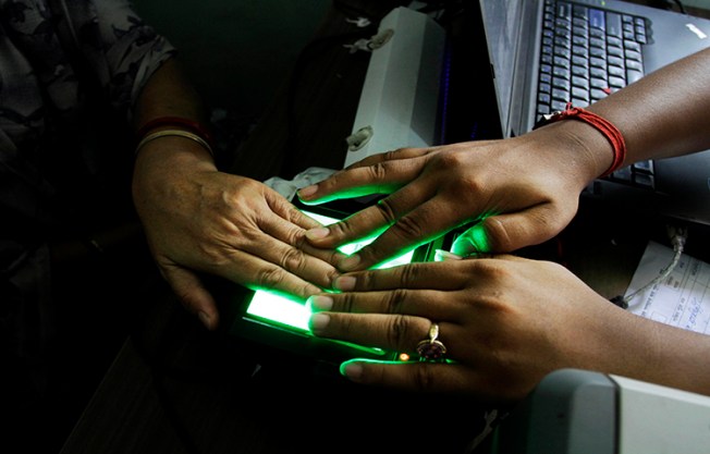 In this May 16, 2012 file photo, an operator helps an elderly woman scan her fingerprints as she enrolls for Aadhar, India's unique identification project in Kolkata, India. The country's leading English-language daily, The Tribune, published an article exposing a possible vulnerability in the system. (AP/Bikas Das)