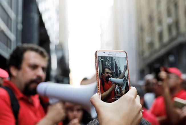 Um telefone celular é usado para filmar um protesto de desabrigados em São Paulo em dezembro de 2017. Antes das eleições de outubro, a polícia é encarregada de combater a proliferação de notícias falsas. (Reuters / Nacho Doce)