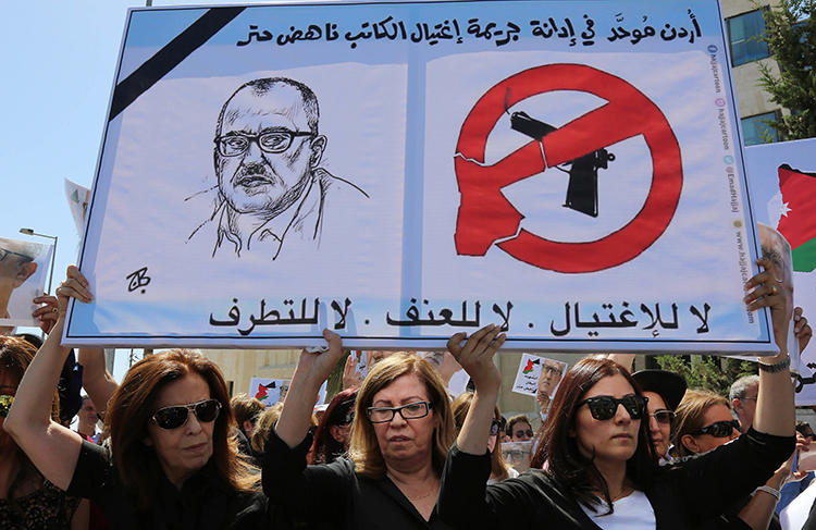 Relatives of Nahed Hattar carry signs condemning his murder during a protest in Amman in September 2016. The Jordanian commentator and writer was shot dead outside a court while on trial for blasphemy over a Facebook cartoon. (AP/Raad Adayleh)