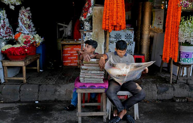 A man reads a newspaper outside a Dhaka flower stall in 2015. Bangladesh's press say a climate of fear amid legal action, attacks, and threats makes covering sensitive issues difficult. (AP)