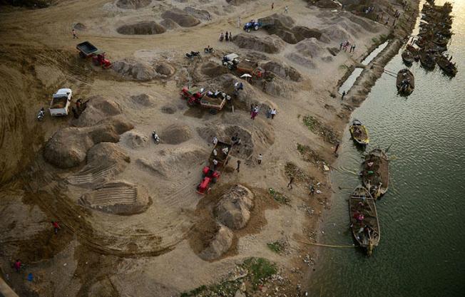 Indian workers use boats to transport sand as they remove it from the River Yamuna in Allahabad in March 2018. Amid growing outrage over the latest murder of a journalist in India, police have arrested a truck driver accused of killing Sandeep Sharma over his investigative reporting into the country's "sand mafia." (AFP/Sanjay Kanojia)