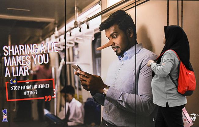 An advertisement at a train station in Kuala Lumpur on March 26 reads 'Sharing a lie makes u a liar.' A draft bill to fight fake news in Malaysia proposes 10-year jail terms for sharing content authorities deem to be false. (AFP/Mohd Rasfan)