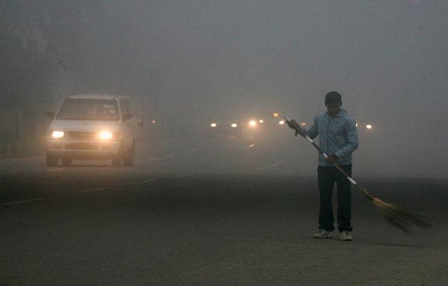 A sweeper cleans a busy road in India's capital New Delhi in January 2011. Two journalists in Bihar state died after a car ran them over on March 25, according to reports. (Reuters/Parivartan Sharma)