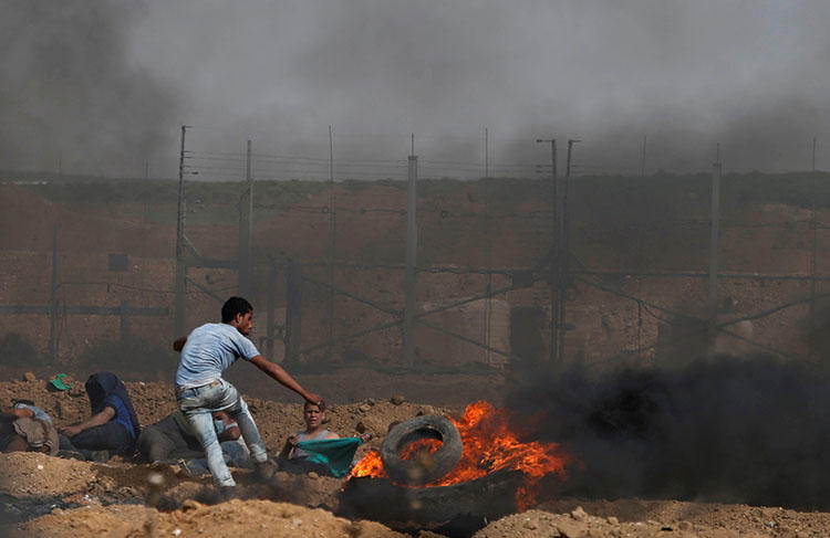 Palestinian demonstrators take cover during clashes with Israeli troops on the Israel-Gaza border, east of Gaza City, April 13, 2018. (Reuters/Mohammed Salem)