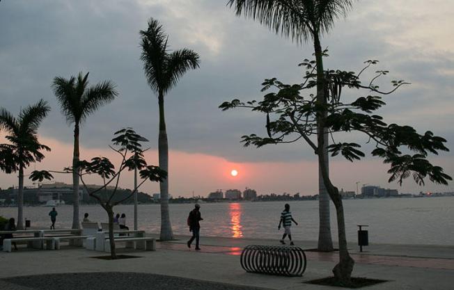 Moradores caminham ao longo da praia durante o pôr do sol na capital de Angola, Luanda, em junho de 2016. O CPJ condenou hoje uma decisão das autoridades angolanas de continuar a portas fechadas, em vez de em tribunal aberto, o julgamento dos jornalistas Rafael Marques de Morais, responsável pelo site de notícias anticorrupção Maka Angola e Mariano Brás Lourenço, correspondente do jornal O Crime. (Reuters / Ed Cropley)