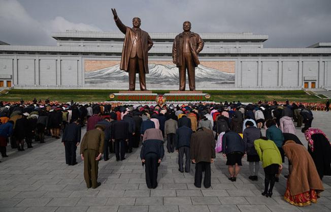 People bow as they pay their respects before the statues of late North Korean leaders Kim Il Sung and Kim Jong Il at Mansu Hill in Pyongyang on April 15, 2018. Eight South Korean journalists were denied entry visas into North Korea to cover the dismantling of a nuclear test site in North Korea, according to news reports. (AFP/Ed Jones)