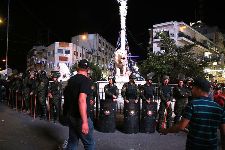 Security officials keep watch during a protest in Ramallah on June 14, 2018. Journalists covering unrest in the West Bank say Palestinian Authority forces attacked and harassed them. (AFP/Abbas Momani)