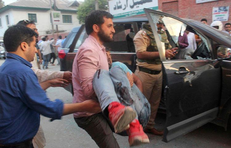 The police bodyguard of journalist Shujaat Bukhari is carried away after an attack in Srinagar, in Indian-controlled Kashmir, on June 14, 2018. Bukhari and two bodyguards were fatally shot as he left his office. (AP Photo)