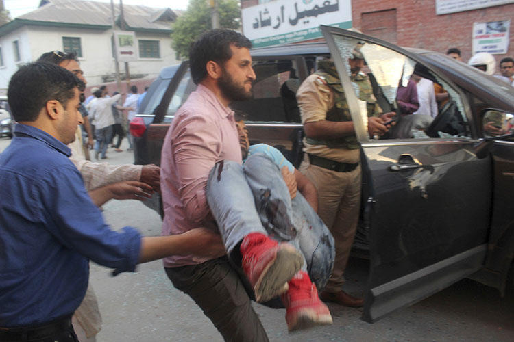 The police bodyguard of journalist Shujaat Bukhari is carried away after an attack in Srinagar, in Indian-controlled Kashmir, on June 14, 2018. Bukhari and two bodyguards were fatally shot as he left his office. (AP Photo)