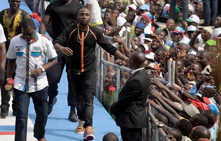 Singer and producer David Adeleke, known as Davido (center) leaves the stage after performing during a political rally in Lagos, Nigeria on January 30, 2015. A member of Davido's private security team assaulted Adekanmbi Damilola, CEO of the online entertainment news platform NoStoryTV, during a concert on July 21, 2018, according to reports. (AFP/Pius Utomi Ekpei)