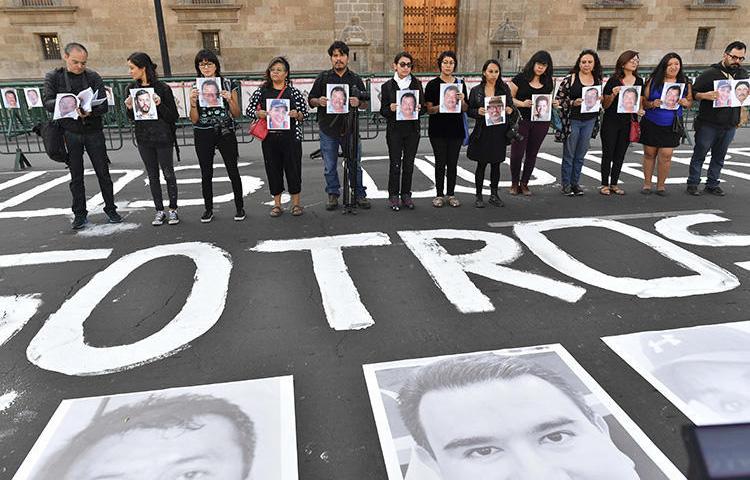 Membros da imprensa seguram imagens de colegas durante protesto contra o assassinato ou desaparecimento de jornalistas e fotojornalistas no México, em frente ao Palácio Nacional na Cidade do México, em 1º de junho de 2018. O jornalista mexicano e proprietário de meio de comunicação Rubén Pat foi morto em Playa del Carmen, no estado de Quintana Roo, no sul do México, em 24 de julho. (AFP/Yuri Cortez)