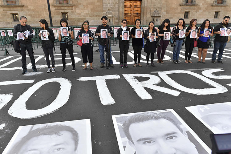 Membros da imprensa seguram imagens de colegas durante protesto contra o assassinato ou desaparecimento de jornalistas e fotojornalistas no México, em frente ao Palácio Nacional na Cidade do México, em 1º de junho de 2018. O jornalista mexicano e proprietário de meio de comunicação Rubén Pat foi morto em Playa del Carmen, no estado de Quintana Roo, no sul do México, em 24 de julho. (AFP/Yuri Cortez)