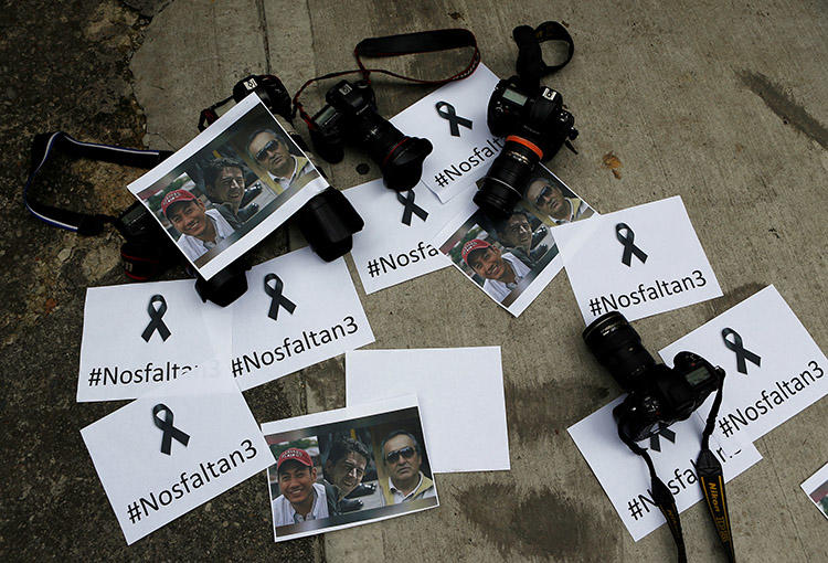 Colombian photographers leave cameras and photos outside the Ecuadoran embassy to protest the killing of journalist Javier Ortega, photographer Paul Rivas, and their driver Efrain Segarra. (Reuters/Jaime Saldarriaga)