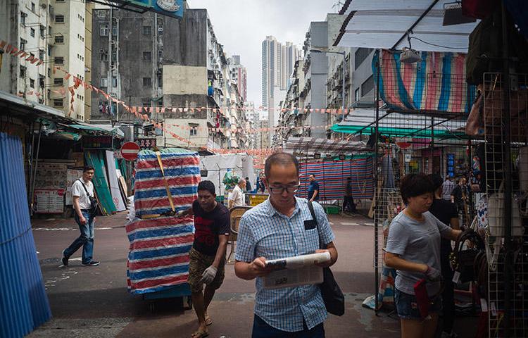 A man reads a newspaper while walking through a market in Hong Kong in May 2018. The Hong Kong Journalists Association says press freedom in the administrative region is in decline. (AFP/Anthony Wallace)