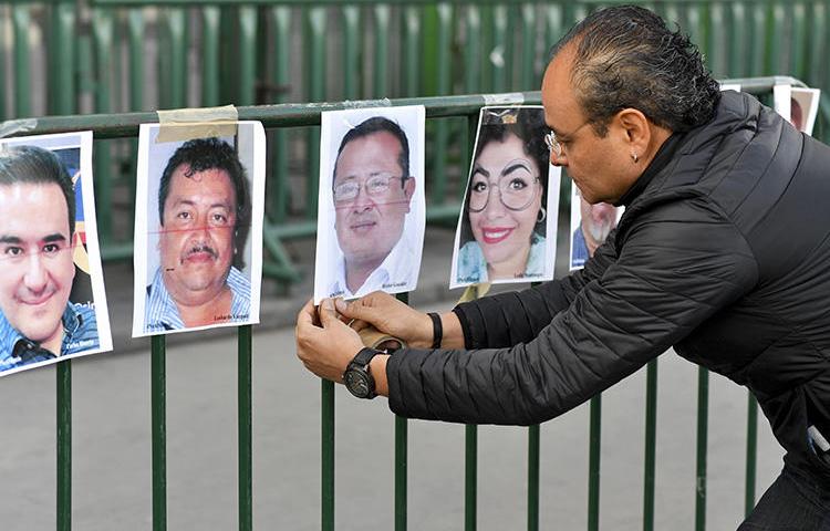 Un periodista cuelga fotos de colegas durante una protesta contra el asesinato o la desaparición de periodistas en México frente al Palacio Nacional en la Ciudad de México el 1 de junio de 2018. El camarógrafo mexicano Javier Enrique Rodríguez Valladares fue asesinado en Cancún, en el sur estado de Quintana Roo, el 29 de agosto. (AFP/Yuri Cortez)