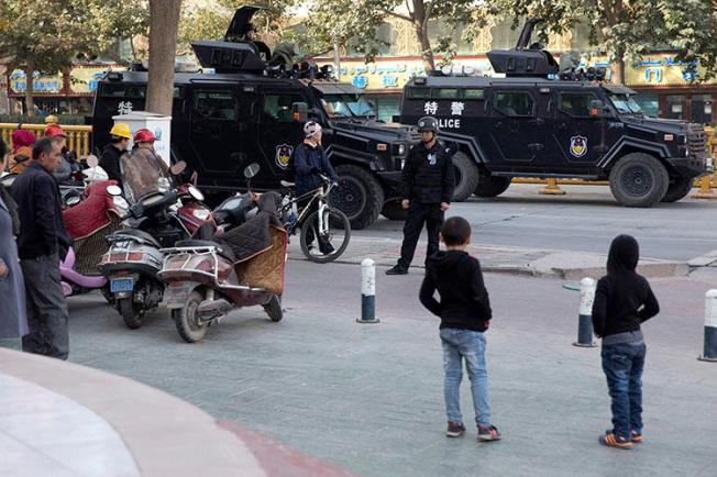 Residents watch a convoy of security personnel and armored vehicles in a show of force through central Kashgar in western China's Xinjiang region in November 2017. China declined to renew the visa of a BuzzFeed journalist who reported on alleged human rights violations in the region. (AP/Ng Han Guan)